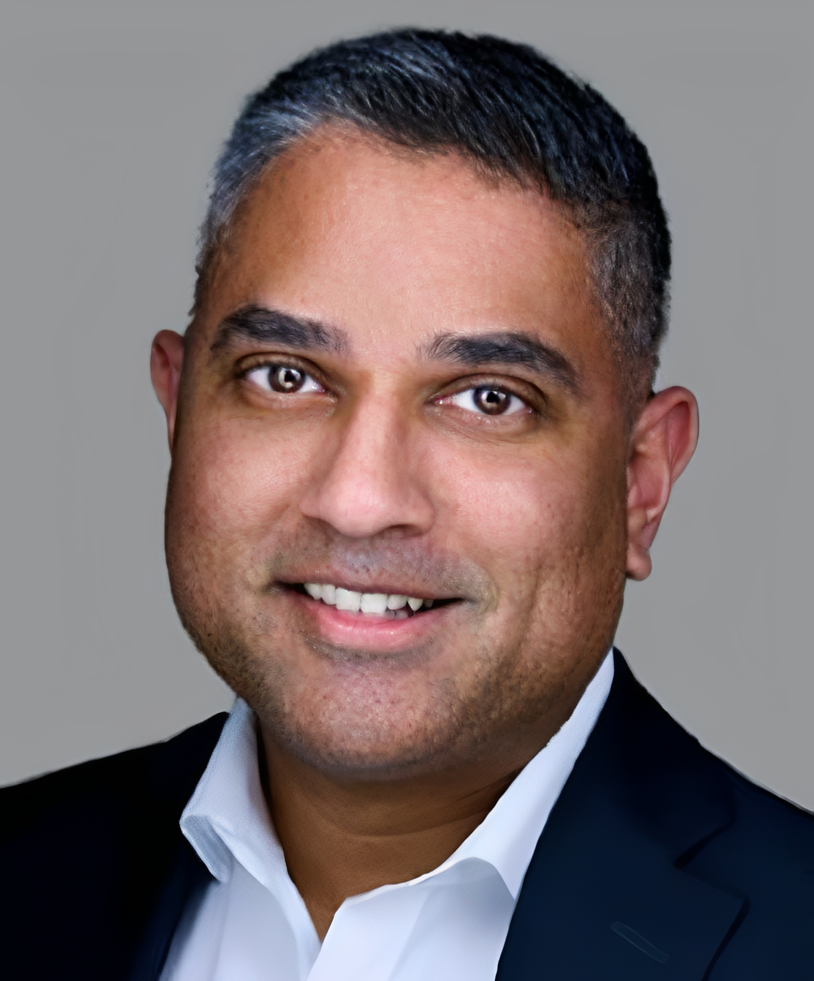 Professional headshot of a smiling man in business attire.